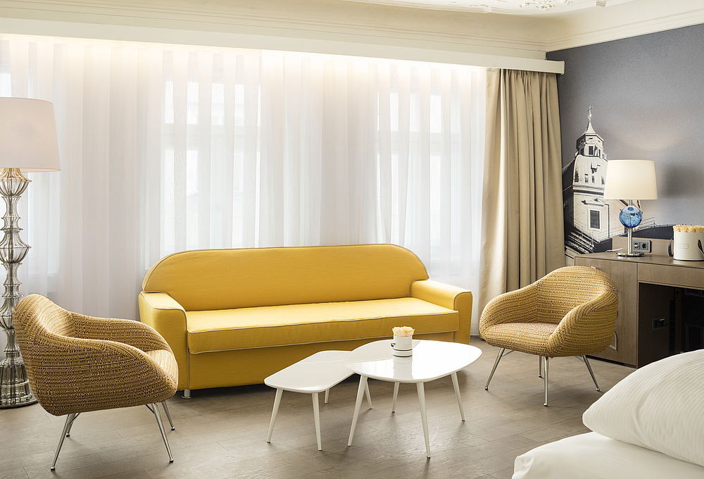 Wohnbereich der Hotelsuite mit gelben Sesseln und Sofa, sowie kleinen weißen Beistelltischen