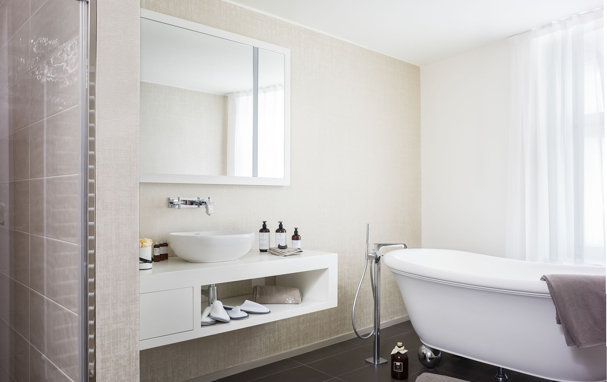 Großzügiges Bad mit Badwanne und modernen weißen Badezimmermöbeln in der Suite des Luxushotel Stein im Zentrum Salzburgs Marmorboden im Badezimmer des Hotel Stein